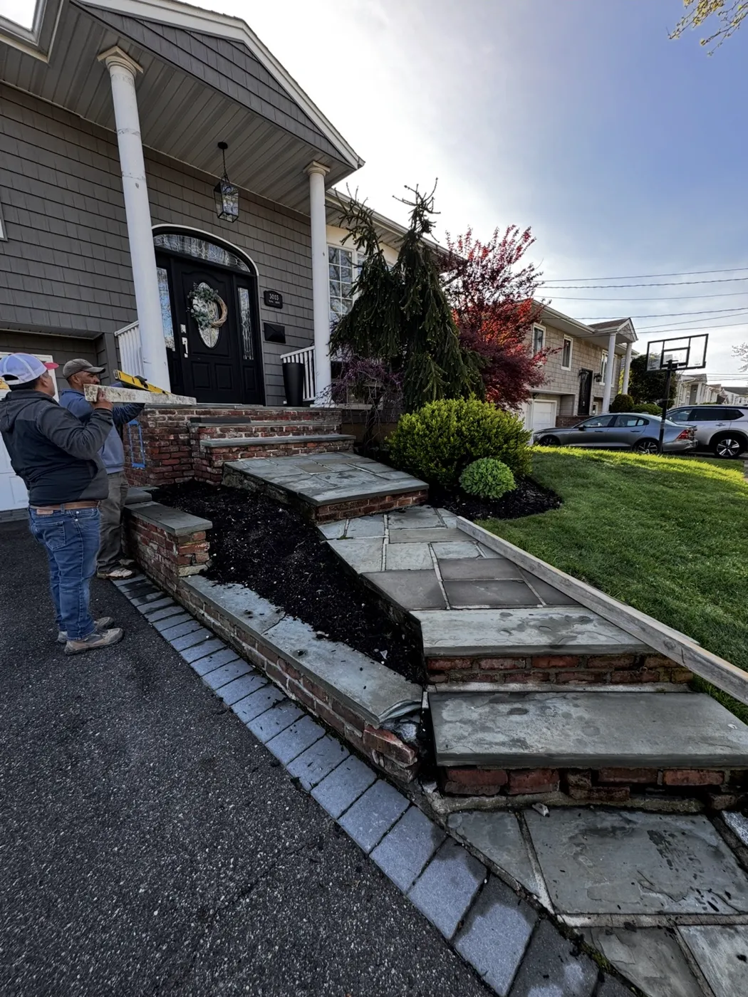 Brick retaining wall with bluestone caps and bluestone steps being rebuilt at a Nassau County NY home