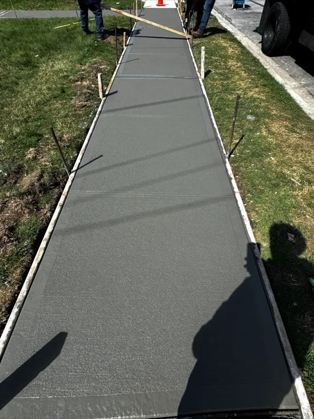 Freshly poured and broom-finished concrete sidewalk with picture-frame edge in Nassau County NY